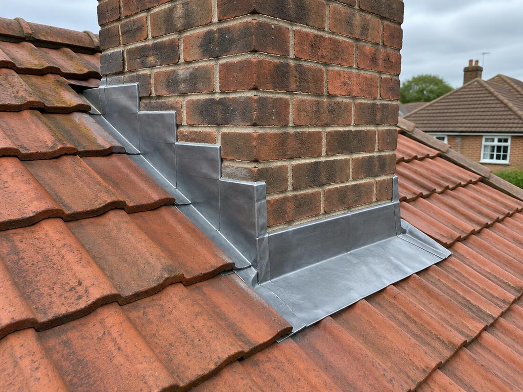 New lead flashing around a brick chimney on a tiled roof